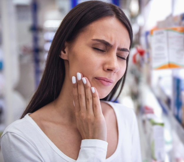 Woman holding her cheek in pain due to a dental emergency near The Dentist Place of Clearwater in Clearwater, FL