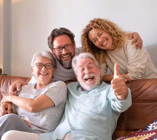 Multi-generational family laughing together on a couch representing comprehensive dental care for all ages at The Dentist Place of Clearwater in Clearwater, FL