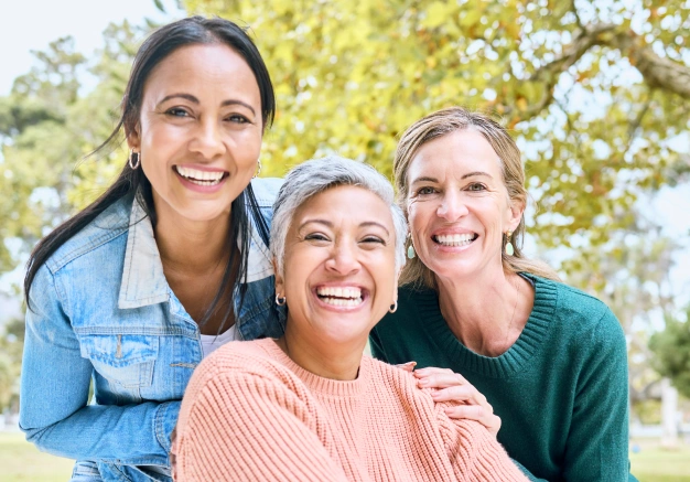 Three women smiling together outdoors as patients of The Dentist Place of Clearwater in Clearwater, FL