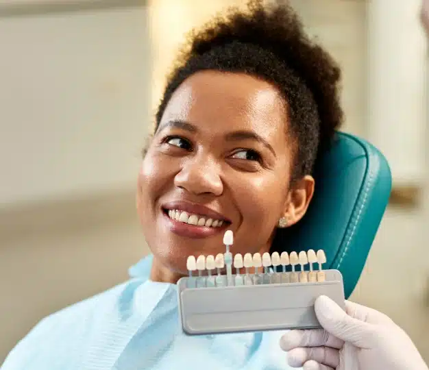 Patient smiling while dentist holds a shade guide for custom dental veneers at The Dentist Place of Clearwater in Clearwater, FL
