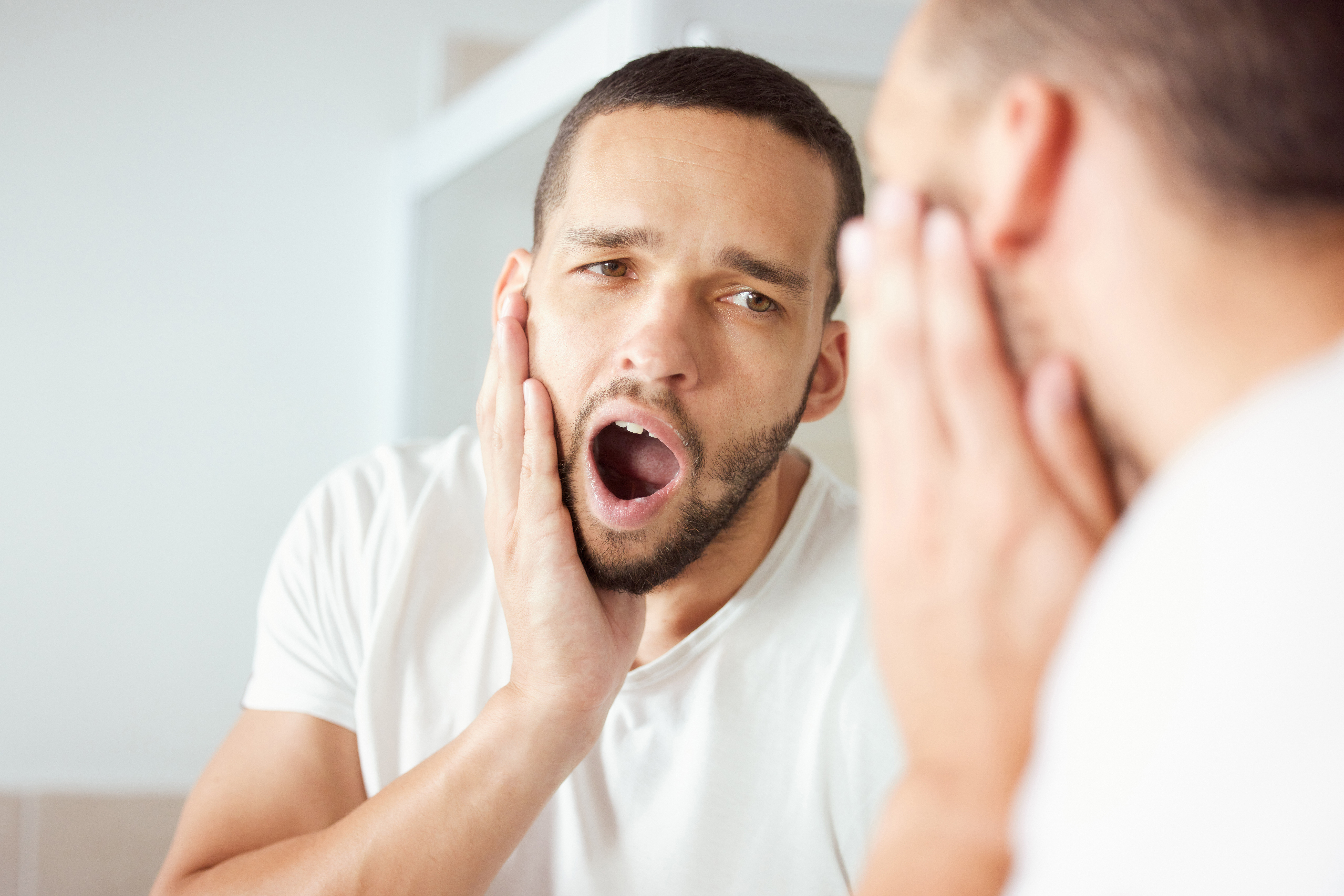 Man holding cheek due to severe nighttime tooth pain
