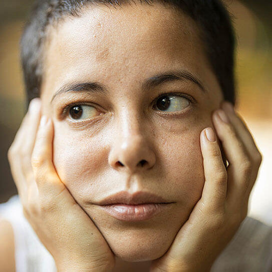 Person with hands on face showing discomfort or dental pain, neutral background.