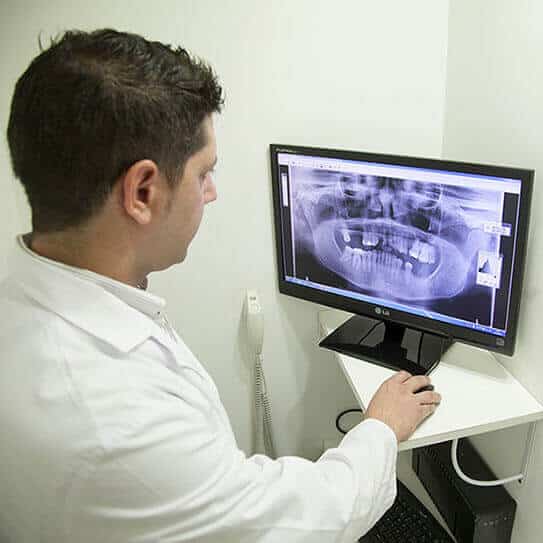 Dentist reviewing dental X-ray on computer monitor in clinical office setting.