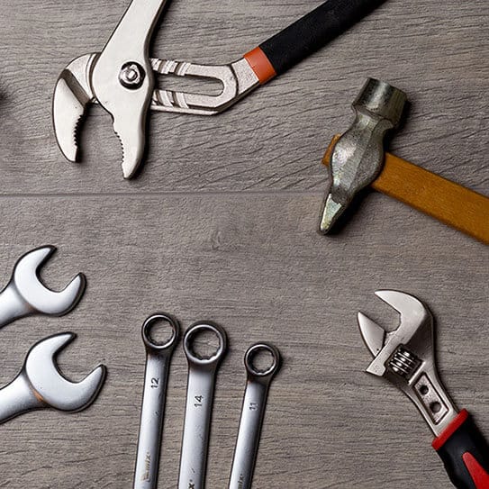 Various wrenches and tools arranged on wooden surface for dental practice equipment.