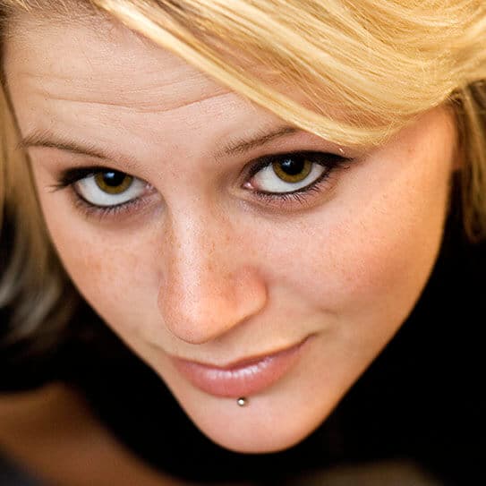 Woman with blonde hair smiling at camera in close-up portrait shot.
