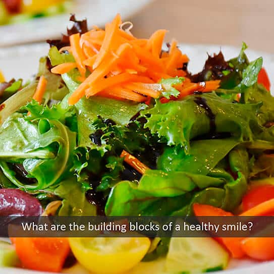 Colorful fresh salad with leafy greens and shredded carrots illustrating healthy eating for dental health.