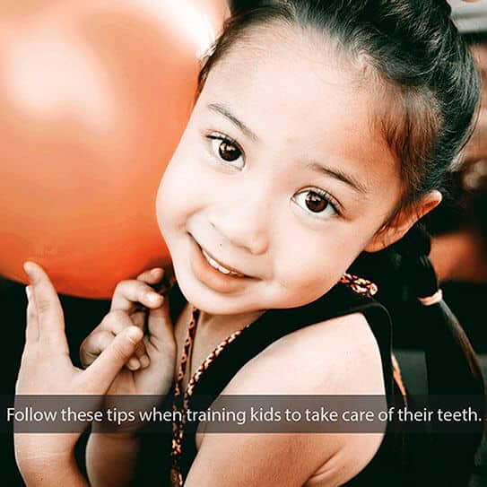 Young girl smiling while holding toothbrush, demonstrating proper dental care and oral hygiene practices.