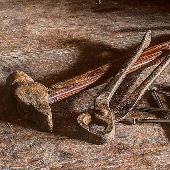 Rusty vintage dental tools and instruments arranged on weathered wooden surface.