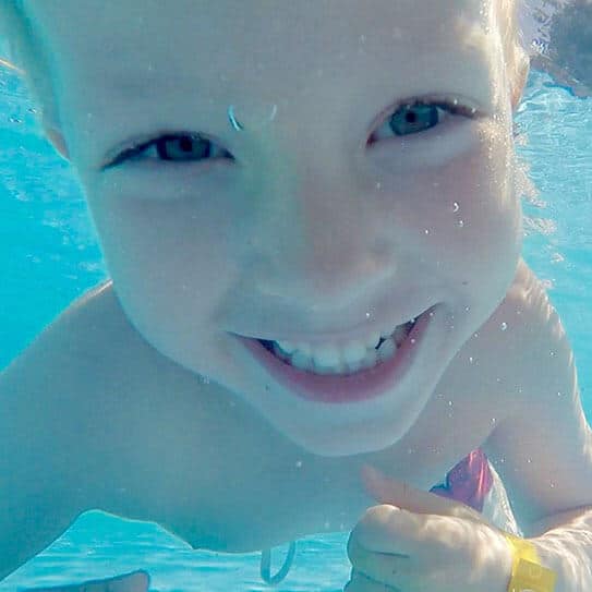 Happy child smiling underwater, promoting pediatric dental care and healthy teeth.