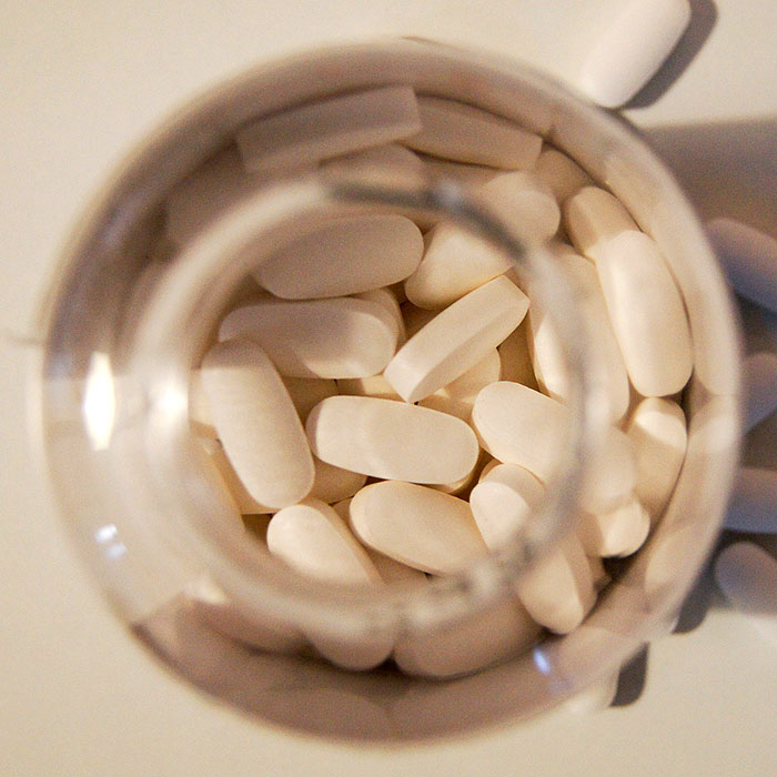 White dental implant pills or supplements in clear container viewed from above.