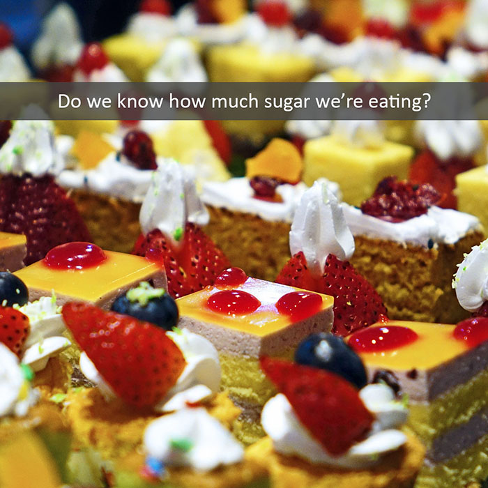 sugar-2022_700.jpg Colorful desserts with fruits and whipped cream topped with text about sugar consumption awareness.