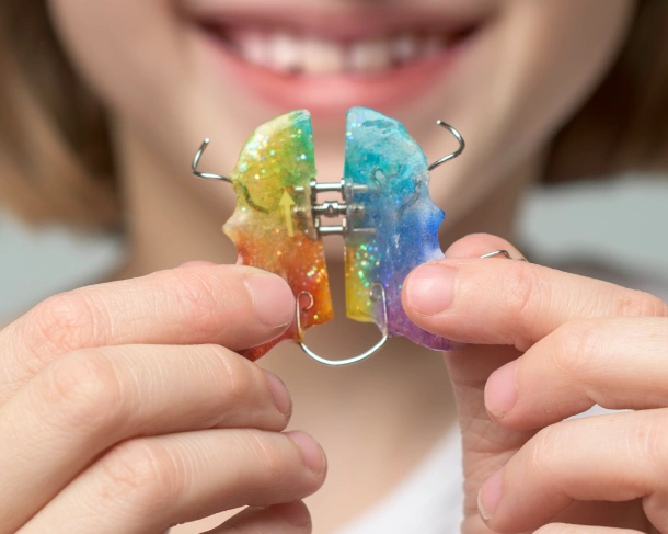A close up of a patient smiling with colorful orthodontic braces at Denver Orthodontics and Dental Lounge in Denver CO