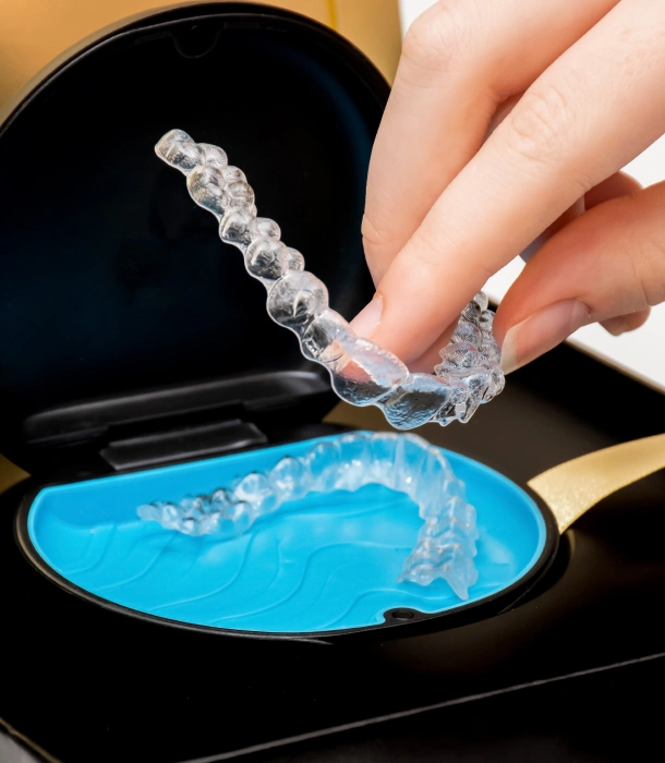 A patient removing a clear aligner from its blue case at Denver Orthodontics and Dental Lounge in Denver CO