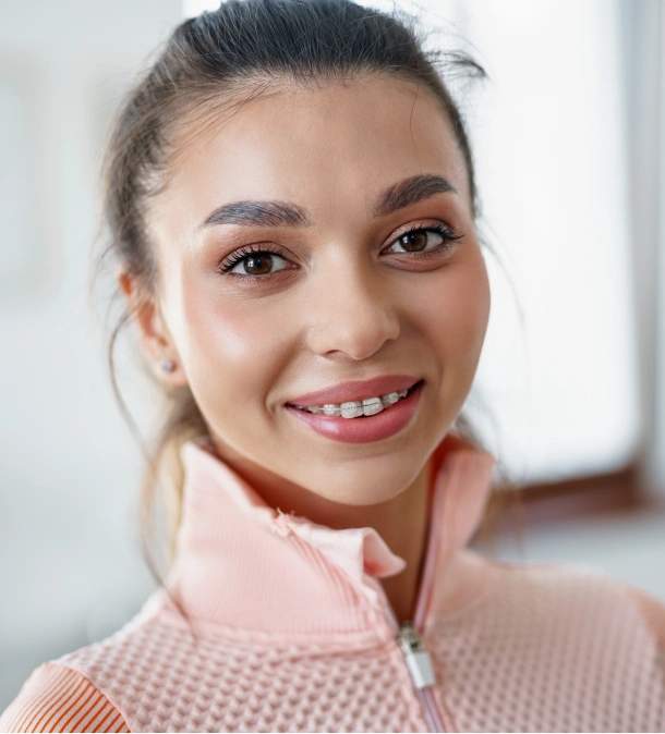 A young girl in a pink top smiling confidently after orthodontic treatment at Denver Orthodontics and Dental Lounge