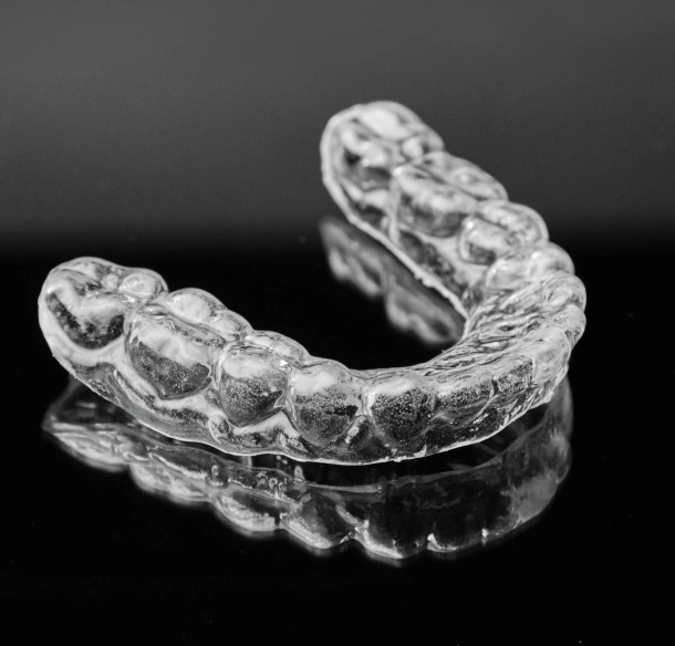 A clear orthodontic aligner tray displayed on a black background at Denver Orthodontics and Dental Lounge in Denver CO