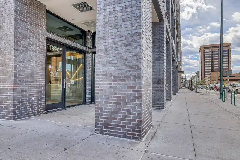 The exterior entrance of Denver Orthodontics and Dental Lounge at 1890 Market Street in Denver CO with brick facade and glass doors