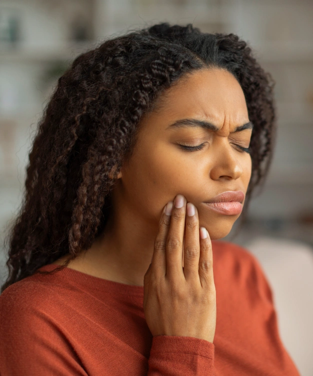 Woman holding her cheek in pain, indicating dental discomfort or emergency toothache.