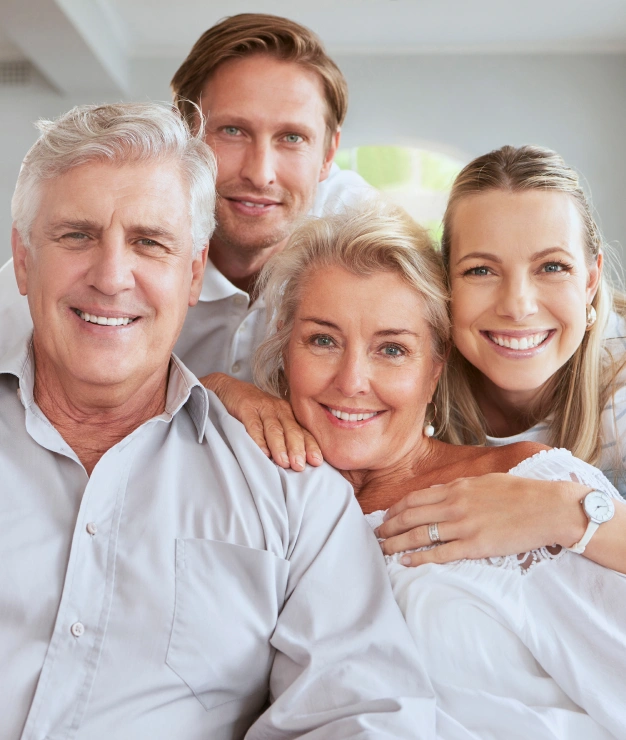 Happy multi-generational family smiling together in bright dental office setting.