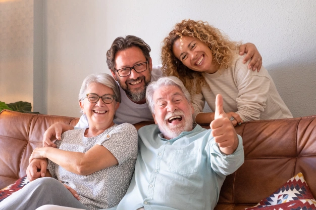 Happy multi-generational family smiling together on couch, representing quality dental care in Clewiston, FL.
