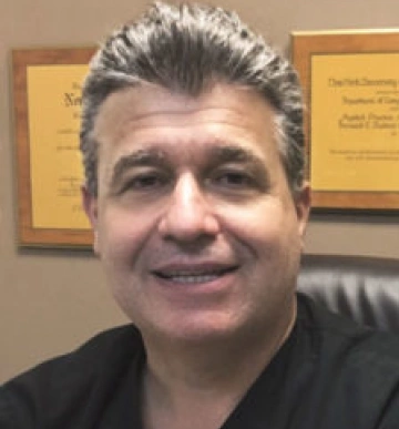 Dr. Gary Salamon, dentist at Clewiston dental practice, smiling in office.