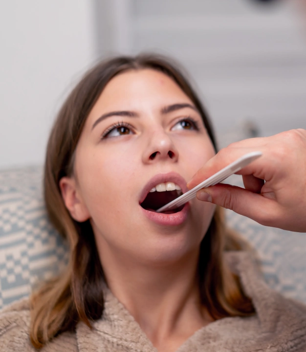 Patient receiving oral examination with tongue depressor during dental evaluation.