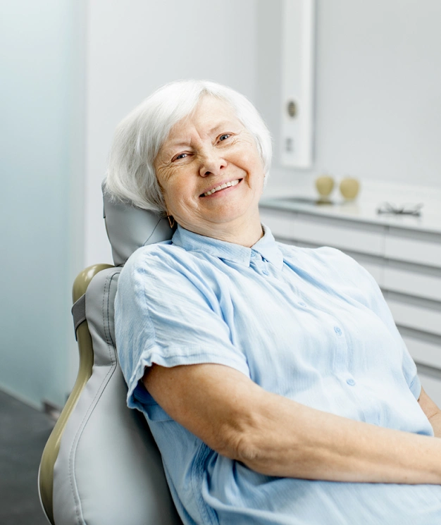 Smiling senior woman relaxing in dental chair after root canal therapy treatment.