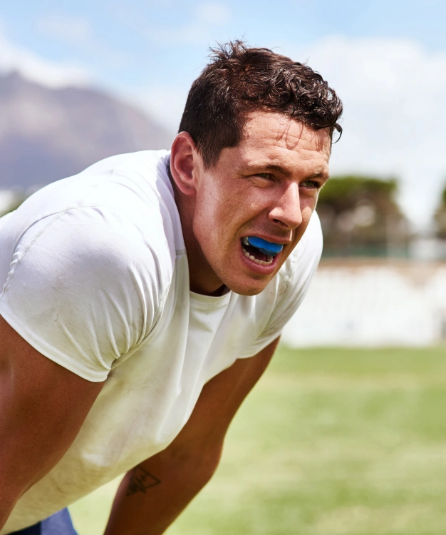 Athlete wearing blue sports mouthguard while exercising outdoors.