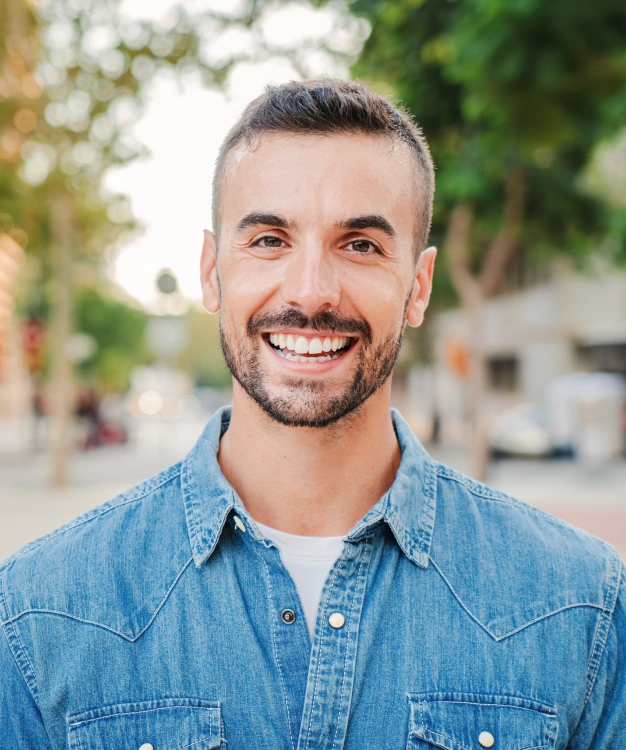 Smiling man in denim shirt at Clewiston dental practice location.