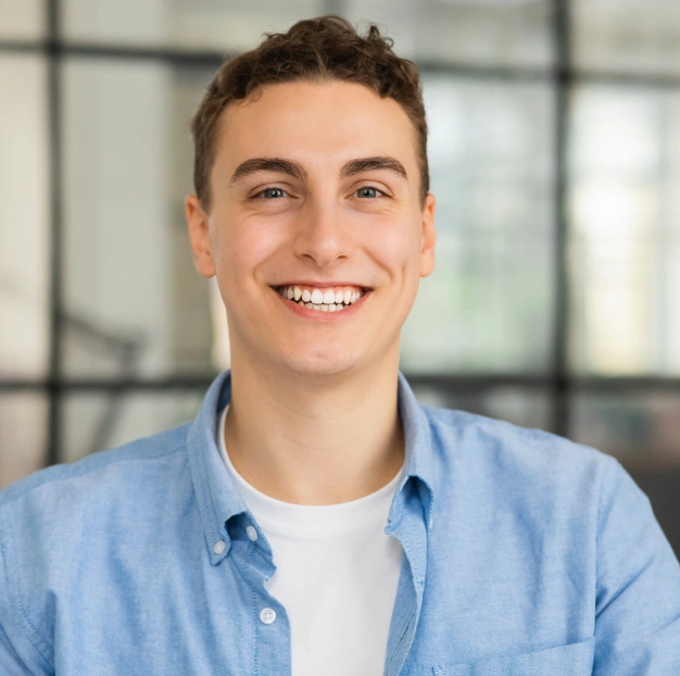 Young man smiling with bright white teeth in dental office setting.