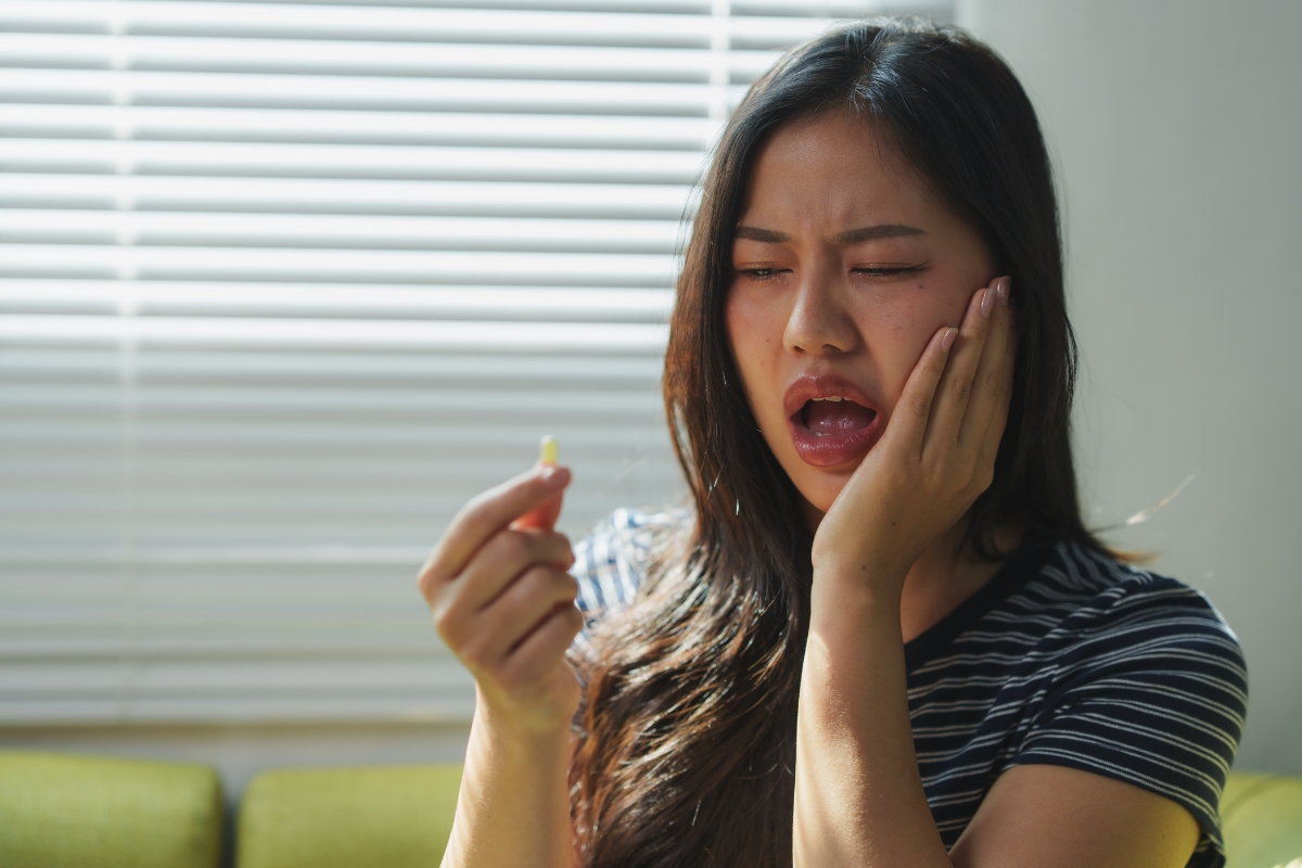 Woman experiencing severe tooth pain and facial discomfort from possible tooth infection symptoms.