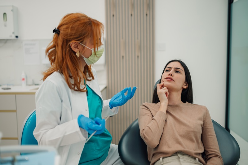 Patient discussing tooth pain and delayed dental treatment with a dentist in a modern Alpharetta dental office.
