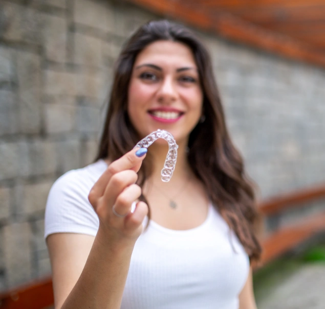 Woman holding an Invisalign clear aligner at Lilburn Smile Makers Dental