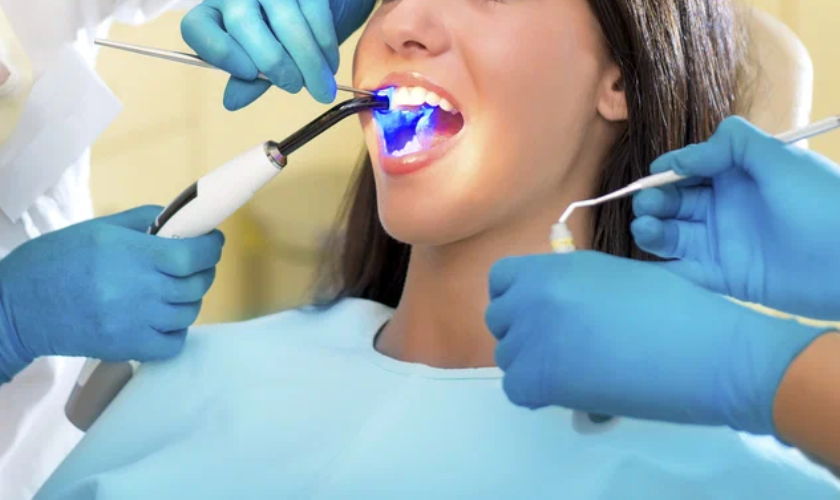 Dentist applying ozone therapy to a patient's teeth using a blue light device