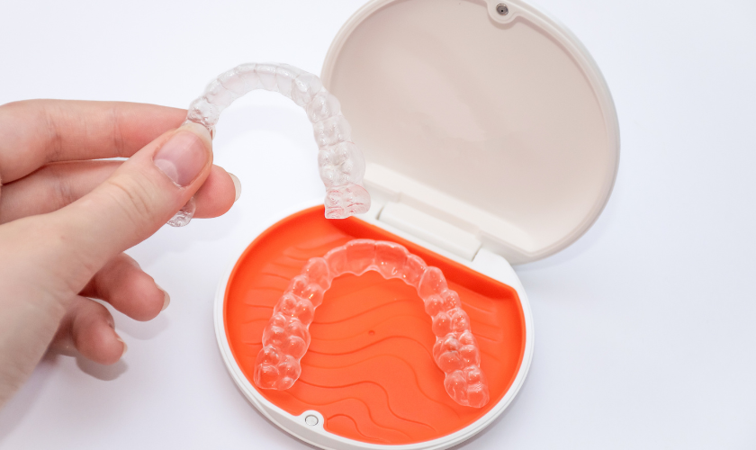 Invisalign and clear aligner trays side by side on a white surface