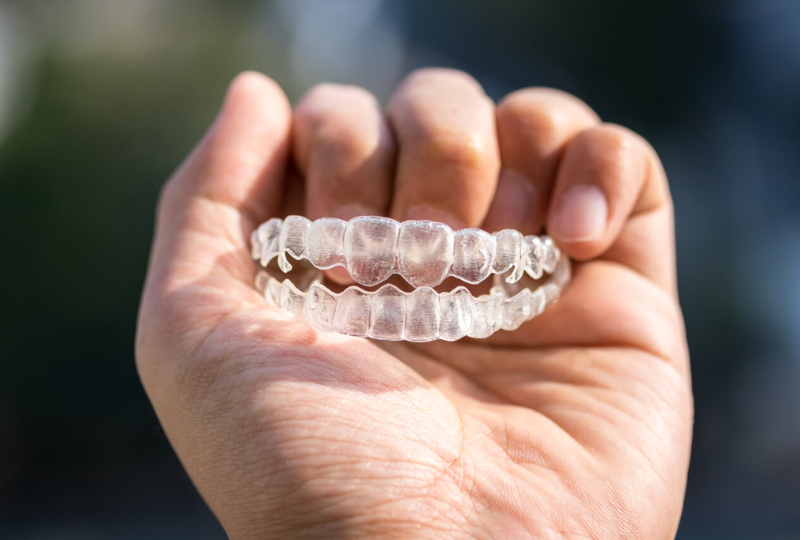 Dentist holding Invisalign clear aligners used for orthodontic treatment