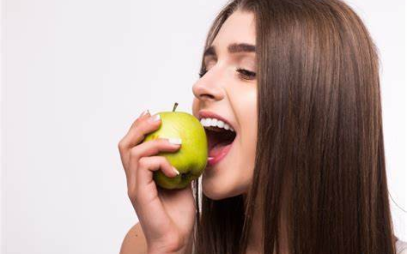 Woman happily biting into a green apple