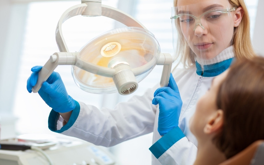 Natural emergency dentist adjusting a dental light before treating a patient
