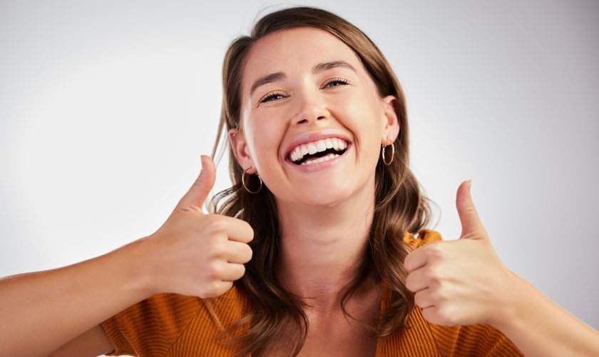 Woman smiling and giving a thumbs up after a dental visit