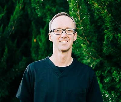 Dr. Cory Harker smiling in front of a dark green background