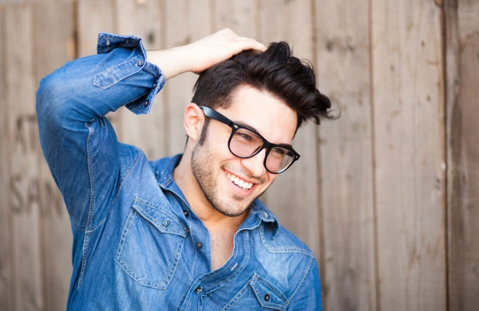 A man with glasses smiling outdoors