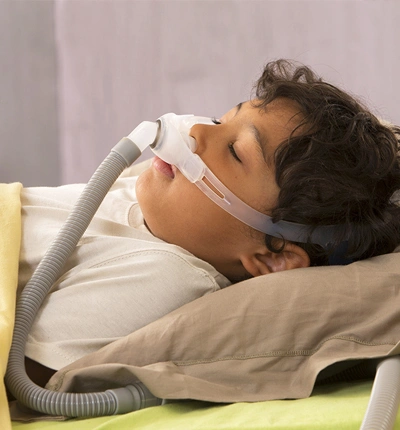 Child sleeping with a breathing device to address sleep disorders