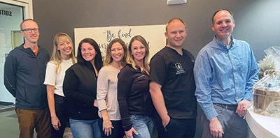 Dental team members smiling at the front desk of a comfort focused dental office