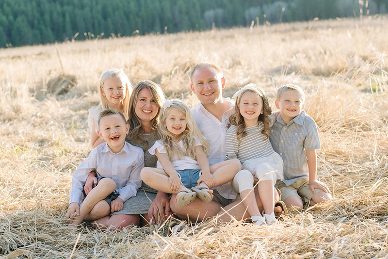 Dr. Bryant Zollinger and his family posing together in a golden field