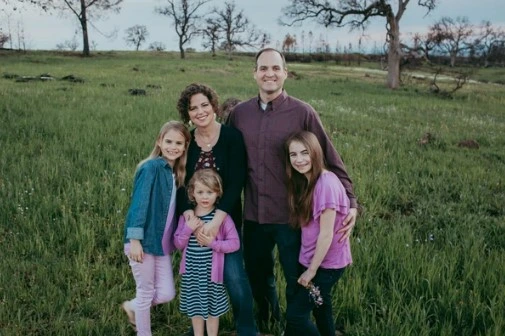 Dr. Jeremy Chatfield and his family standing together in a grassy field