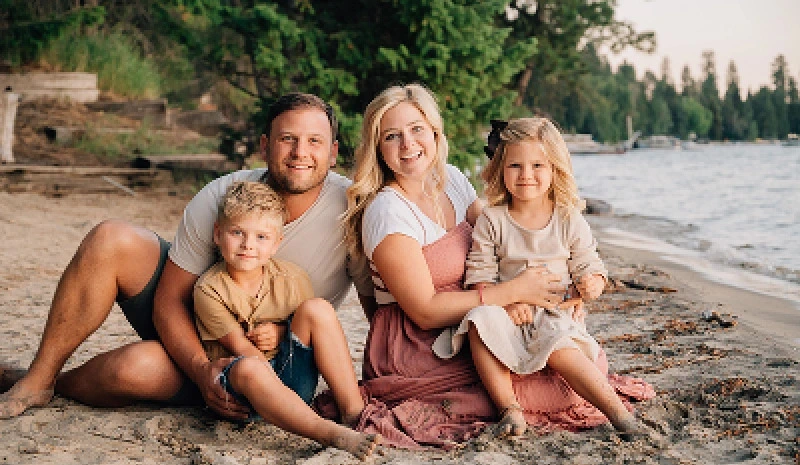 Dr. Taylor Zollinger and his family sitting together on a beach