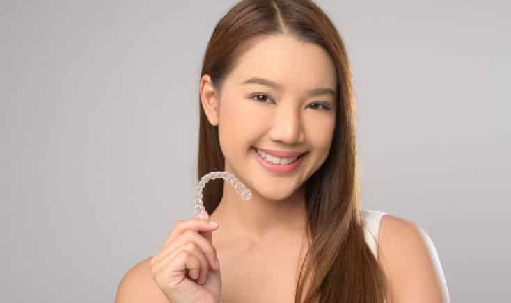 smiling woman holding Invisalign