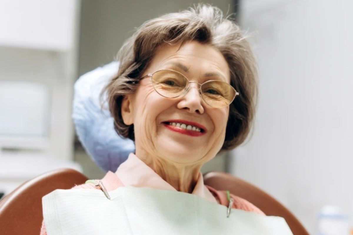 Senior woman with glasses smiling after successful dental treatment