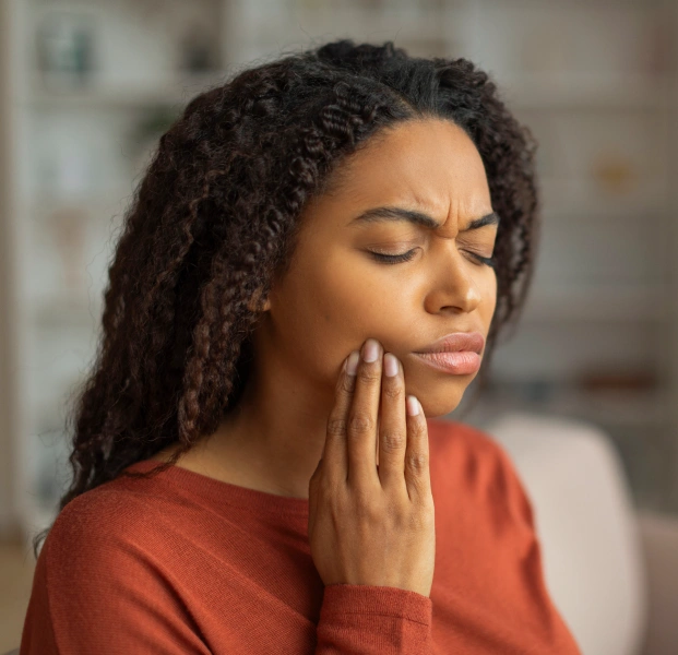 Woman touching jaw experiencing tooth pain or dental discomfort