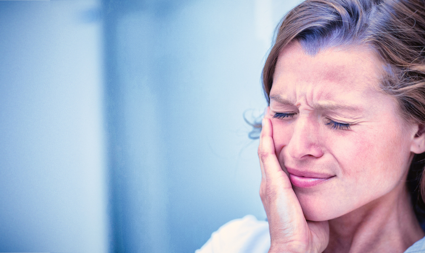 Person holding cheek in pain from toothache on a rainy day in Bellevue, WA