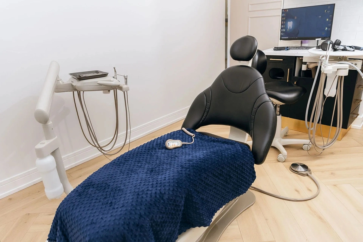 Comfort amenities including noise-canceling headphones, sunglasses, and remote laid out on blue blanket at Seven Bridges Dental Studio